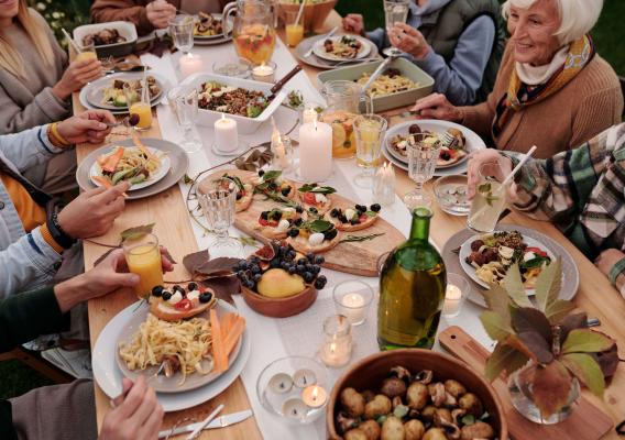 A family enjoying a meal while seated at a table covered with different foods and beverages