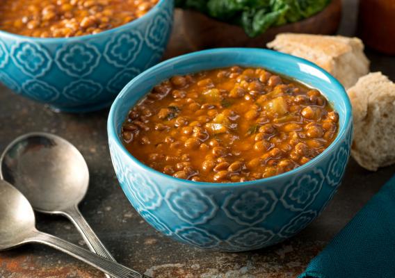 A blue bowl filled with lentil soup on a table