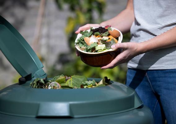 A person throwing out food into the trash