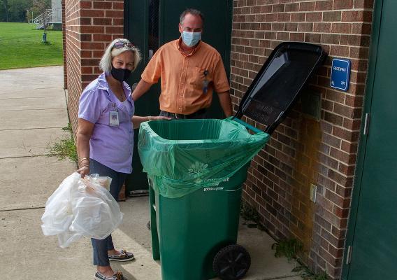 Two people near a compost bag at a school