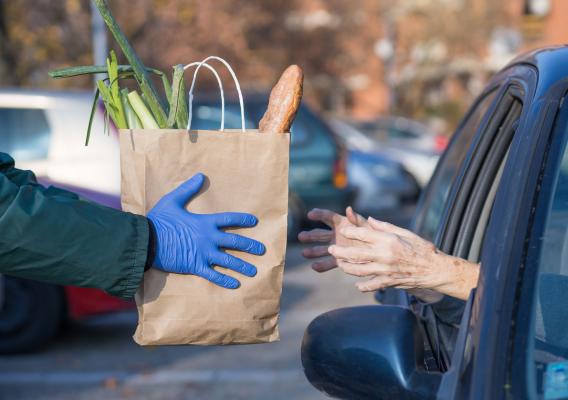 Paper bag with essential nutrition supplies given to elderly person at food distribution point