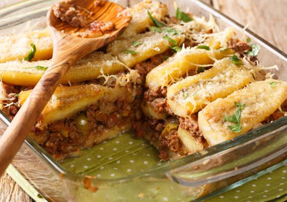 A baking dish containing pastelón, a Puerto Rican casserole with layers of yellow plantains, ground beef, vegetables, and cheese