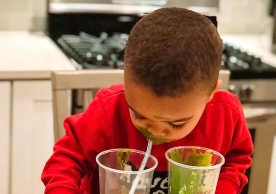 Young boy sipping a fruit smoothie from a cup