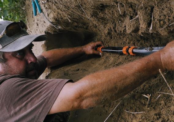 Roland Hill III works to replace damaged drip tape lines during a hot summer day in July 2019