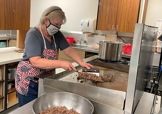 Norma Miller, Prospect Head Cook, preparing lunch by cooking ground meat on a griddle