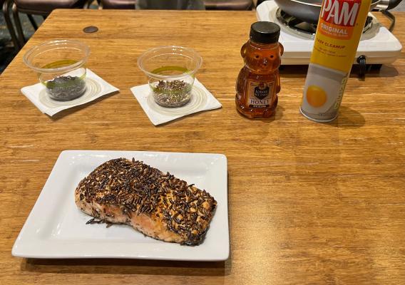 A filet of salmon encrusted in a wild rice coating rests on a white plate