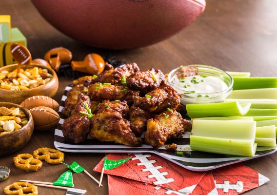 A platter of chicken wings, celery, snack mix and dipping sauce