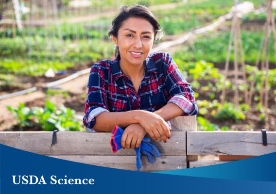 Woman standing in front of rows of crops on a small farm