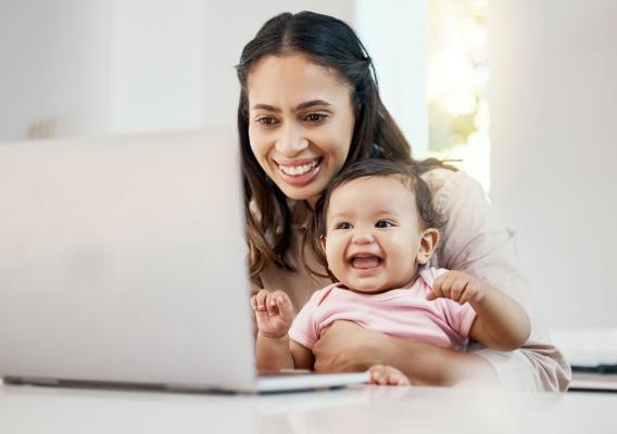 Mom and baby smiling while looking at a computer screen