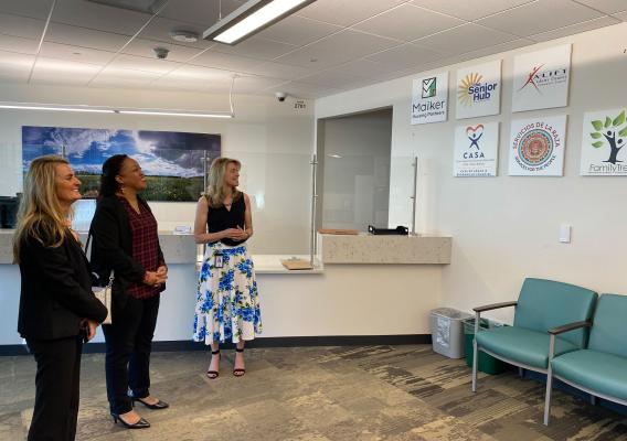 Three women look at partner organization signs in an office